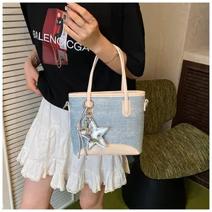 Détail du sac cabas en denim bleu clair avec garniture en cuir beige et étoile à paillettes