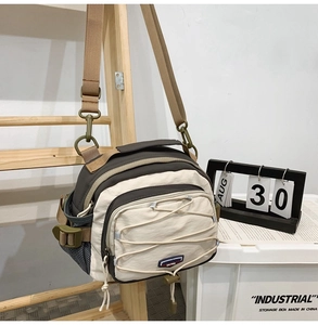Detail of crossbody tote bag featuring ivory and brown panels with elastic bungee cords
