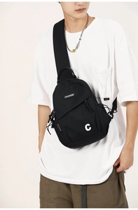 Detail of black nylon chest bag with multi-pocket layers and branded letter C print