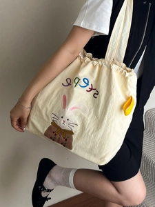 Minimalist canvas tote bag with rabbit embroidery shown on model for casual daily use