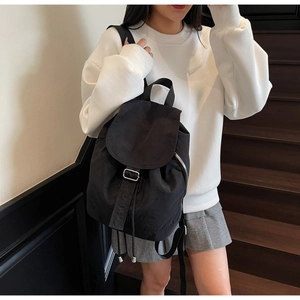 Détail d'un sac à dos en nylon noir imperméable avec cordon de serrage et boucle en métal