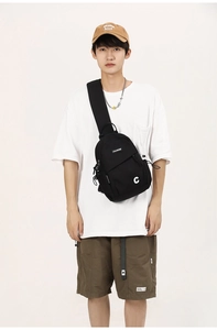 Close-up of black canvas crossbody bag with letter C detail worn by a model