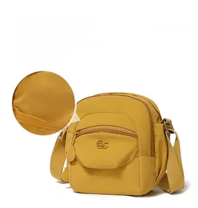 Détail du sac bandoulière en nylon jaune montrant la doublure et la poche zippée avant