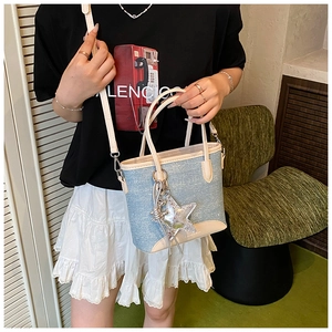 Détail d'un sac cabas en denim avec garniture en cuir blanc et breloque étoile argentée