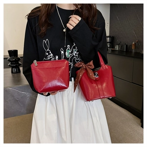 Dettaglio della borsa a secchiello in pelle lucida rossa e pochette con fiocco decorativo