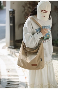 Close-up of khaki large capacity canvas crossbody bag with adjustable strap and logo