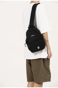 Detail of black nylon chest bag with CHUANGMI label and adjustable wide strap