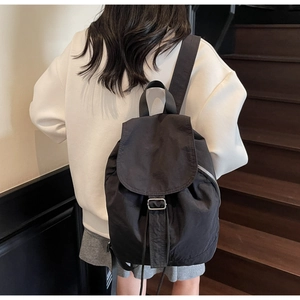 Détail du sac à dos en nylon noir avec cordon de serrage et boucle métallique argentée