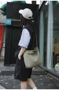 Detail of khaki nylon drawstring crossbody bag with pleated texture and front pocket