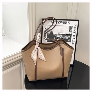 Detail of an earth-tone pebble leather tote bag with a geometric silk scarf on handle