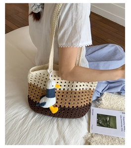 Detailed close-up of handmade knit tote bag with seagull charm and hollow weave texture