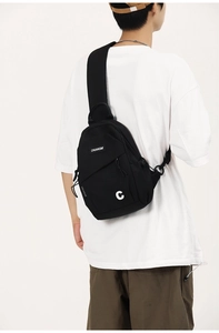 Close-up of black canvas chest bag with white 'C' logo and wide shoulder strap