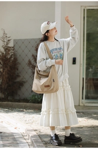 Outdoor shot of a beige canvas messenger bag worn by a model in a trendy casual style