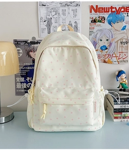 Detail of cream backpack with pink star print showing drawstring side pockets and zippers