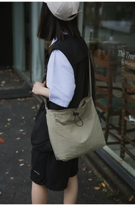 Outdoor street style view of a person wearing a green drawstring nylon shoulder bag