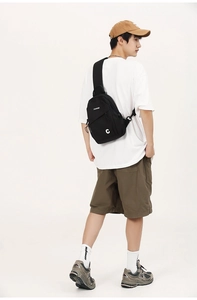 Detail view of large black nylon crossbody bag with multi-zipper layers and drawstring