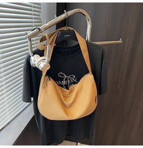 Nahaufnahme der ingwergelben Segeltuch-Halbmondtasche an einem Shirt mit Kopfhörern