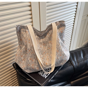 Detail of floral lace tote bag with blue base, wide straps and exquisite embroidery