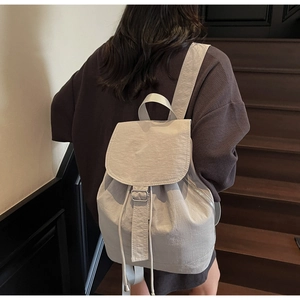 Détail d'un sac à dos gris clair imperméable avec cordon de serrage et boucle en métal