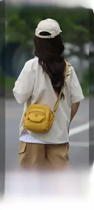 Détail d'un sac bandoulière en nylon jaune gingembre avec fermetures éclair et sangle