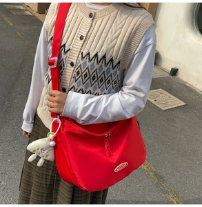 Detailed view of red nylon crossbody bag with adjustable strap and cloud charm pendant