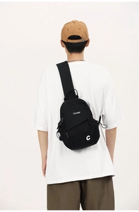 Model wearing a black canvas crossbody chest bag with adjustable strap and multi-zipper pockets