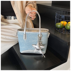 Gros plan d'un sac cabas en denim bleu clair avec breloque étoile sur escalier noir