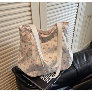 Close-up of floral canvas tote bag with delicate lace overlay and wide shoulder straps