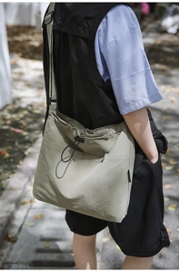 Detail of army green nylon crossbody bag showing drawstring closure and adjustable strap