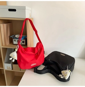 Detail of red and black nylon dumpling bags featuring a cute plush mushroom charm and strap