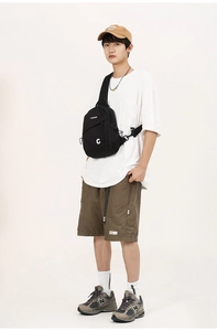 Detail of black crossbody chest bag featuring adjustable strap and white brand logo