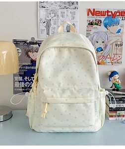 Detail view of cream canvas backpack with blue star patterns and side drawstring pockets