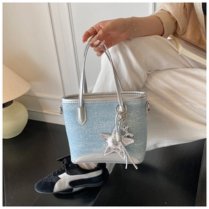 Détail du sac seau en denim bleu clair avec garniture argentée et charm étoile
