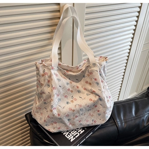 Detail of floral lace tote bag with a zipper closure and cream fabric handles on a sofa