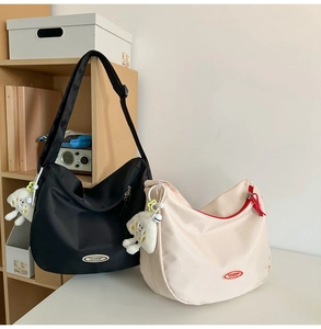 Detail of waterproof nylon crescent bags in black and beige with plush cloud charms