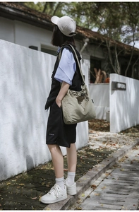 Detail of olive green nylon drawstring shoulder bag with large exterior pockets for travel