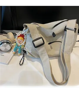 Detail view of off-white nylon crossbody bag with BANATU logo and cute charm accessory