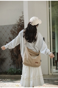 Close-up of khaki nylon messenger bag showing adjustable strap and brown leather logo