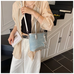 Détail du sac cabas en denim à paillettes bleu clair avec breloque étoile et cuir argenté