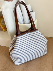 Minimalist canvas tote bag with blue stripes and brown leather straps for daily commute