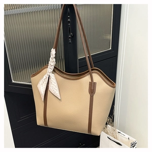 Detail of beige faux leather tote bag with brown trim and floral scarf on handle