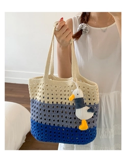 Detail of hand-woven crochet tote bag with blue tricolor stripes and plush gull pendant