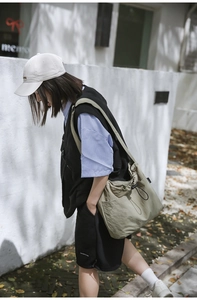 Detail of khaki nylon drawstring bucket bag with natural pleats and wide shoulder strap