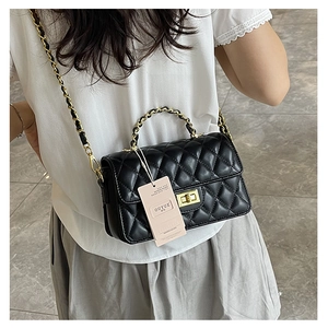 Detail of black quilted leather crossbody bag with gold chain strap and top handle