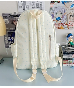 Detail view of canvas backpack back with padded straps and blue star patterns on desk