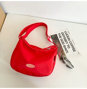 Close-up of red nylon half-moon crossbody bag with adjustable strap and zip closure