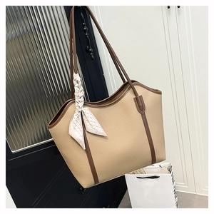 Detail of beige tote bag with brown trim and decorative silk scarf on the handle