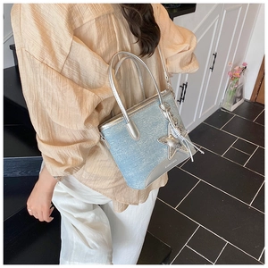 Détail du sac bandoulière en jean bleu clair avec breloque étoile et poignée argent