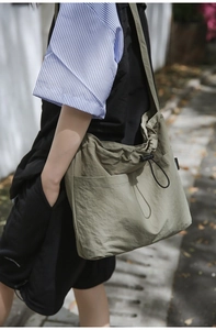 Detail view of olive green nylon drawstring shoulder bag with functional adjustable side buckle