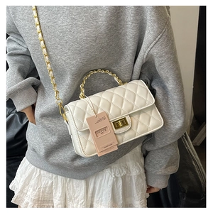Close-up of white quilted crossbody bag with gold chain strap and metal lock detail
